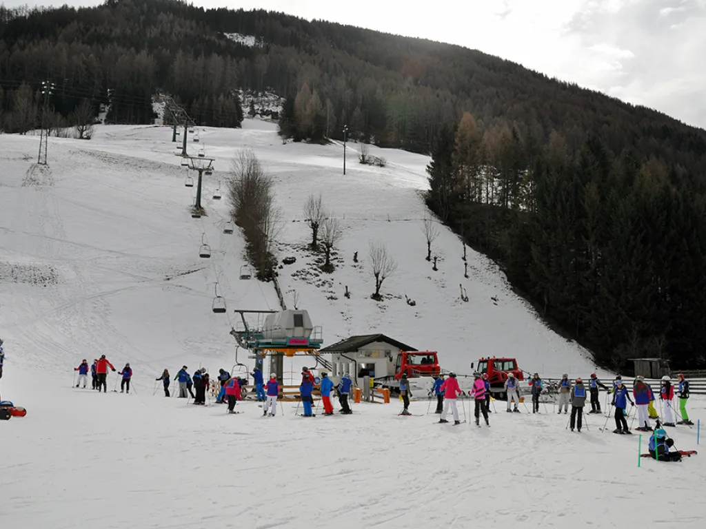 Blick über die Piste zur Talstation mit vielen Wartenden.